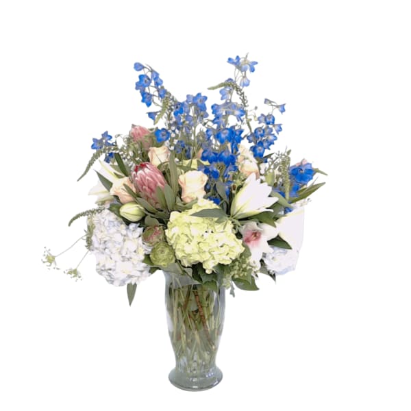 Mixed bouquet of blue and pastel flowers in a clear glass vase