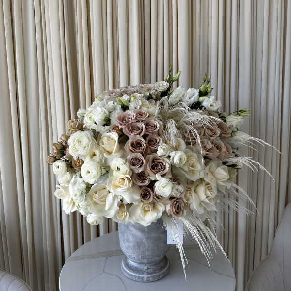 Large cream and blush rose arrangement in a gray urn vase