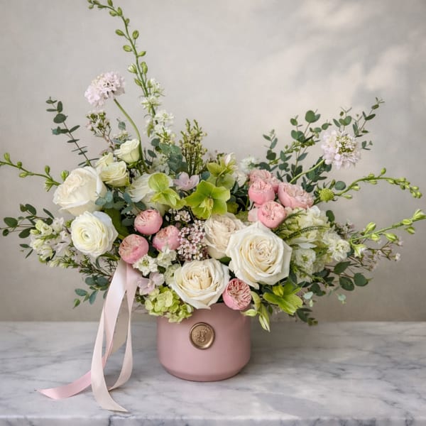Pink and white floral arrangement in a blush vase with ribbon