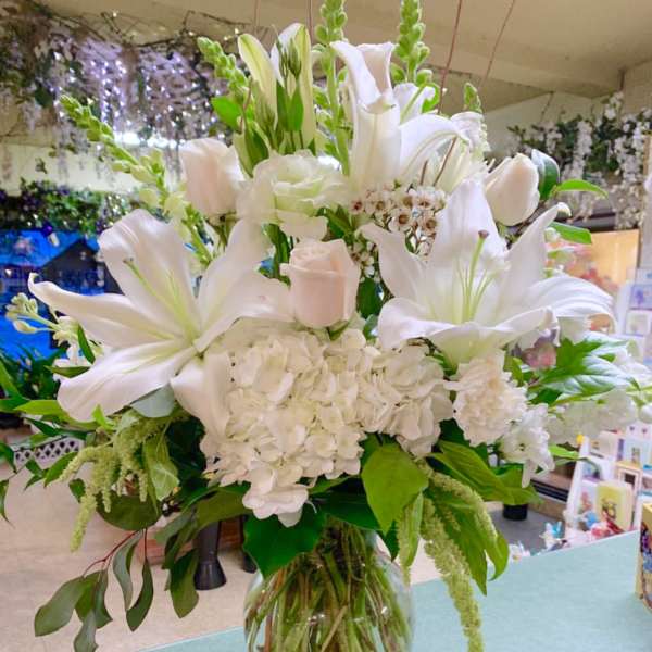 White lilies and hydrangeas arranged in a clear glass vase
