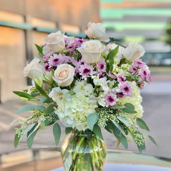 Bouquet of white roses, pink daisies, and hydrangeas in a glass vase