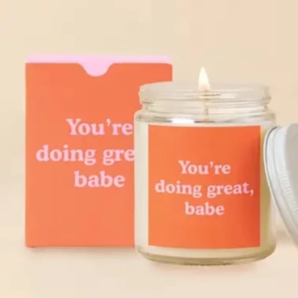 Lit candle in a glass jar beside an orange box