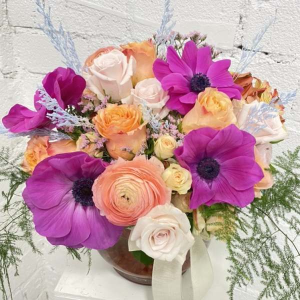Bright mixed bouquet of pink, peach, and white flowers in a glass vase
