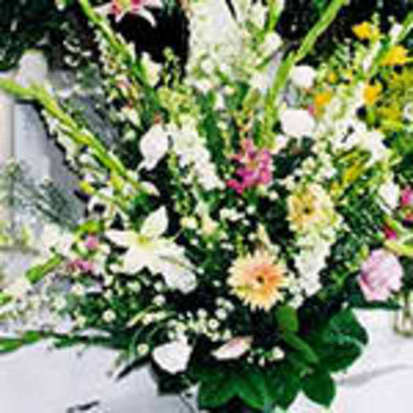 Tall mixed arrangement of white lilies and pastel flowers in a lush, fan-shaped display