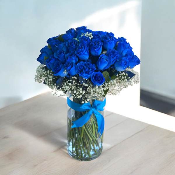 Blue roses arranged in a clear glass vase with a blue ribbon
