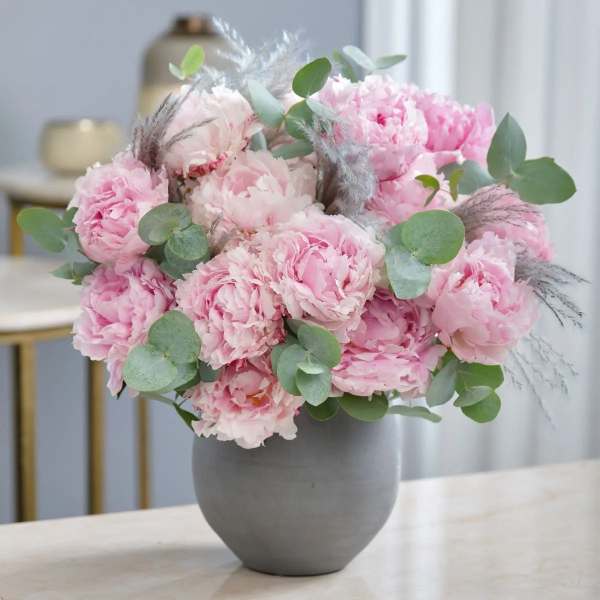 Pink peony bouquet in a gray vase with eucalyptus