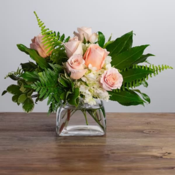 Pink roses and white flowers in a clear glass vase