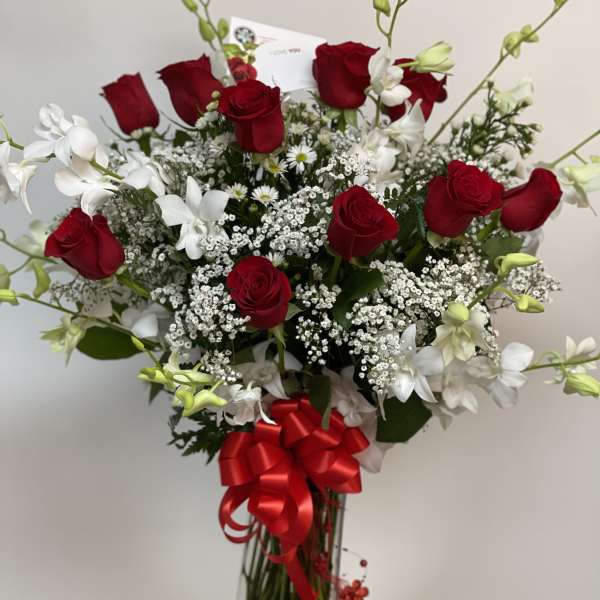 Roses and orchids in curved tall vase