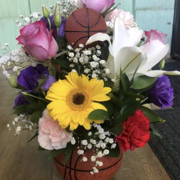 Basketball-themed bouquet with roses, lilies, and a yellow gerbera daisy