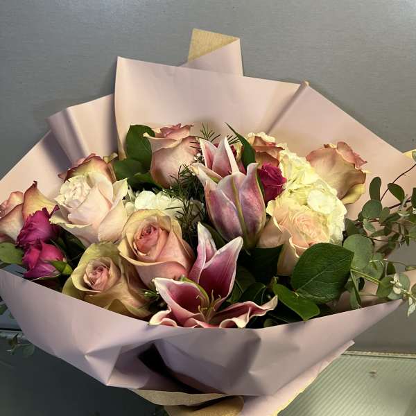 Bouquet of pink roses and lilies wrapped in pale pink paper