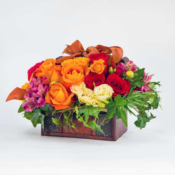 Orange and red roses in a decorative wooden box with ivy