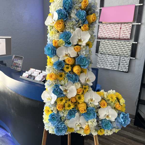 Tall floral standing arrangement with blue, yellow, and white blooms on an easel