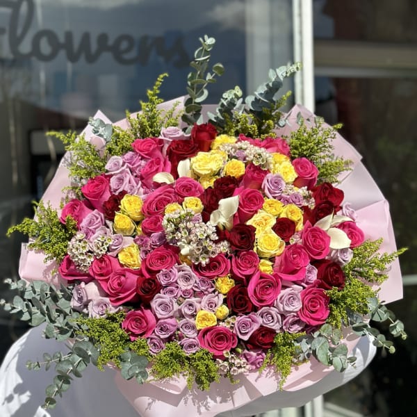 Large bouquet of pink, red, yellow, and lavender roses with eucalyptus