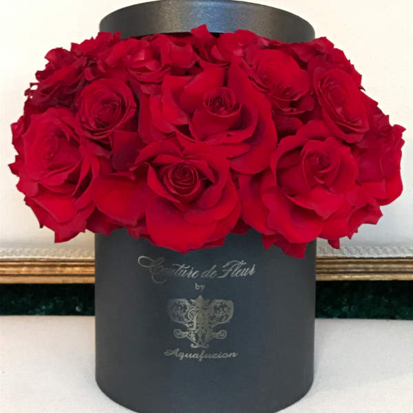 Red roses arranged in a black round hat box