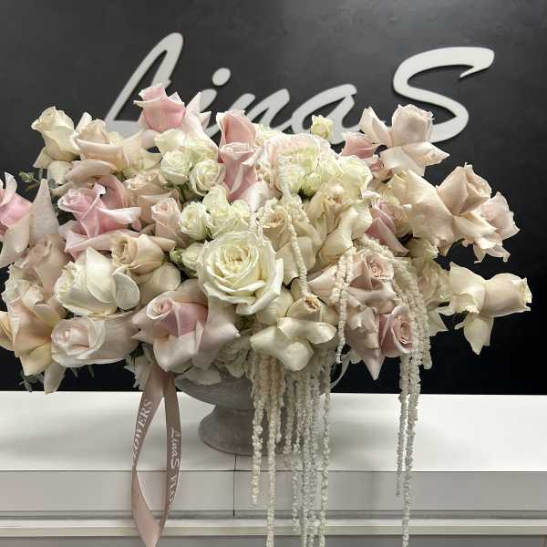 Large pastel rose arrangement in a gray pedestal vase