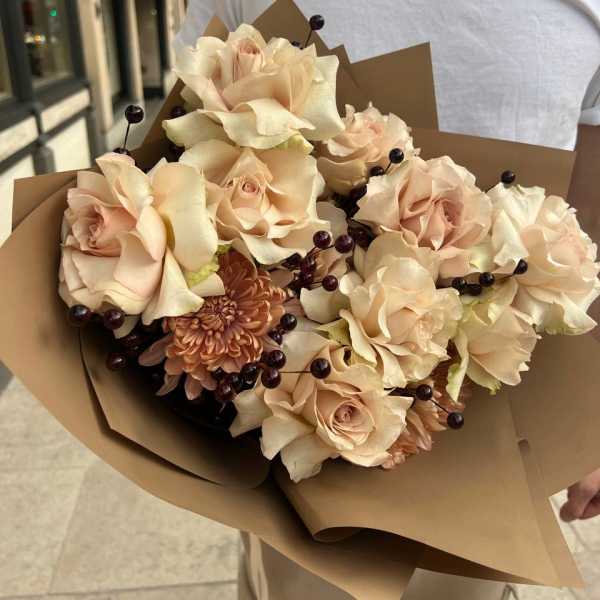 Bouquet of pale peach roses and a chrysanthemum wrapped in brown paper