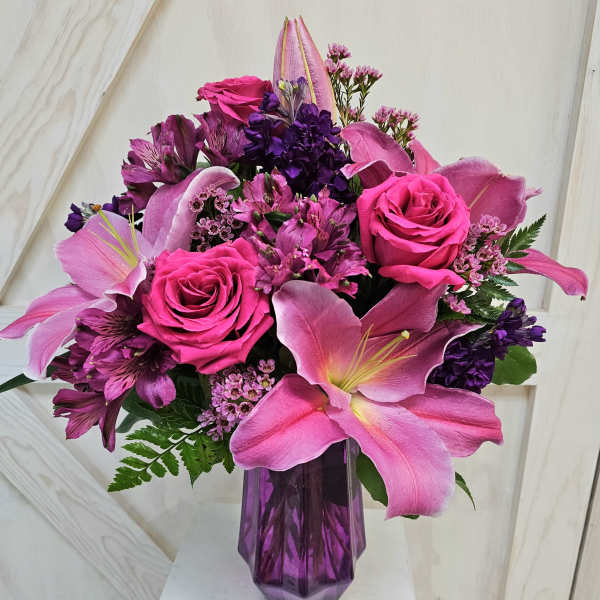 Pink and purple bouquet with roses and lilies in a purple vase
