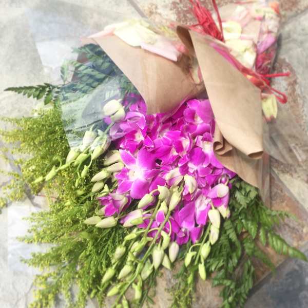 Bouquet of purple orchids with green filler wrapped in brown paper