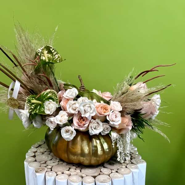 Floral arrangement with roses and anthuriums in a gold pumpkin container