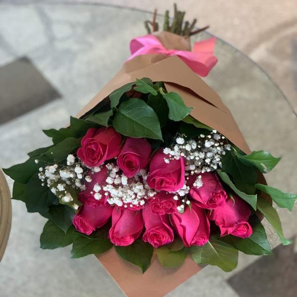 Bouquet of hot pink roses with baby's breath wrapped in brown paper