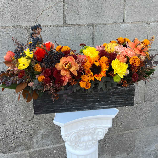 Autumn floral arrangement with sunflowers, mums, and berries in a black container