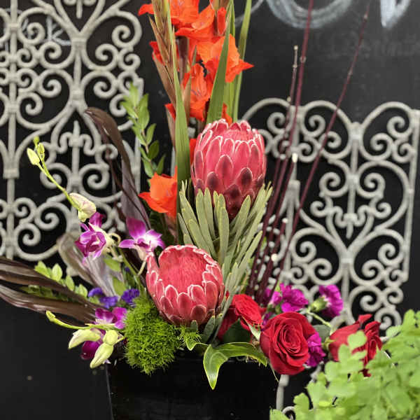 Tall tropical floral arrangement with red protea and orange blooms