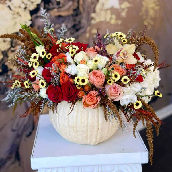 Mixed roses and small daisies arranged in a white pumpkin vase