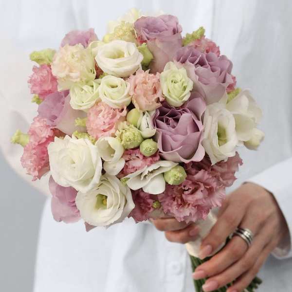 Handheld bouquet of blush, lavender, and white roses with pink ruffled blooms