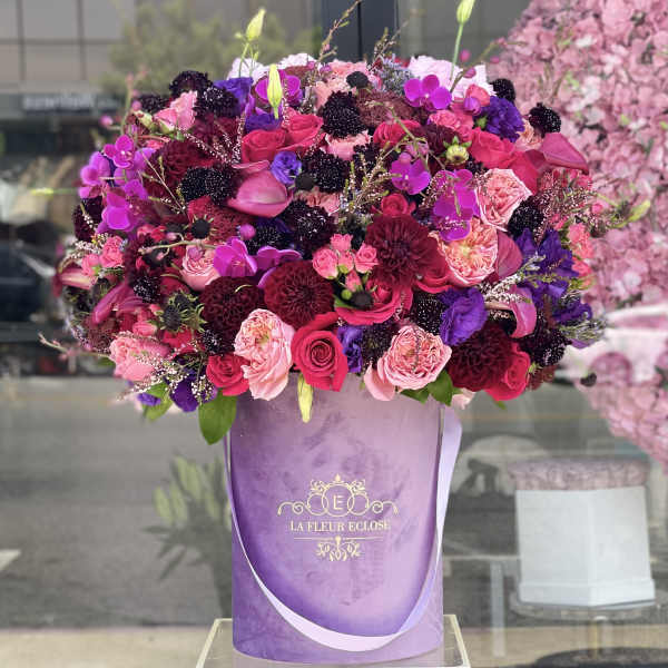 Large bouquet of pink, purple, and burgundy flowers in a lavender box