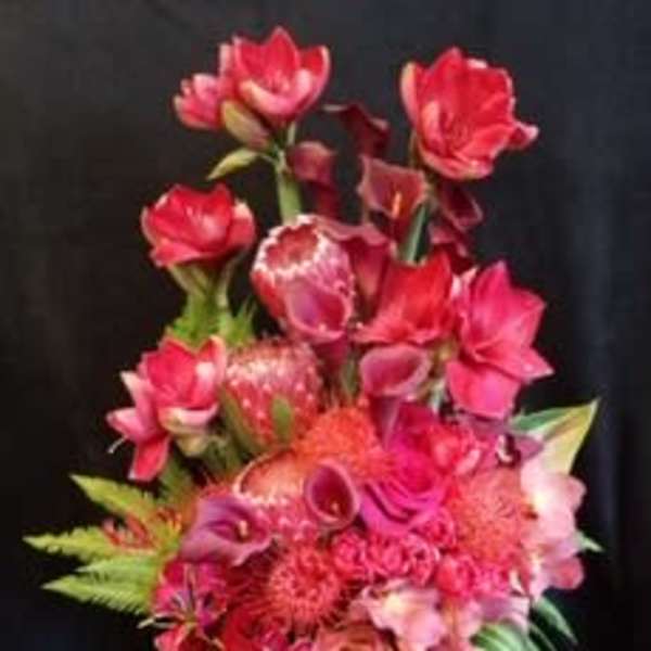 Tall pink and red floral arrangement in a green vase