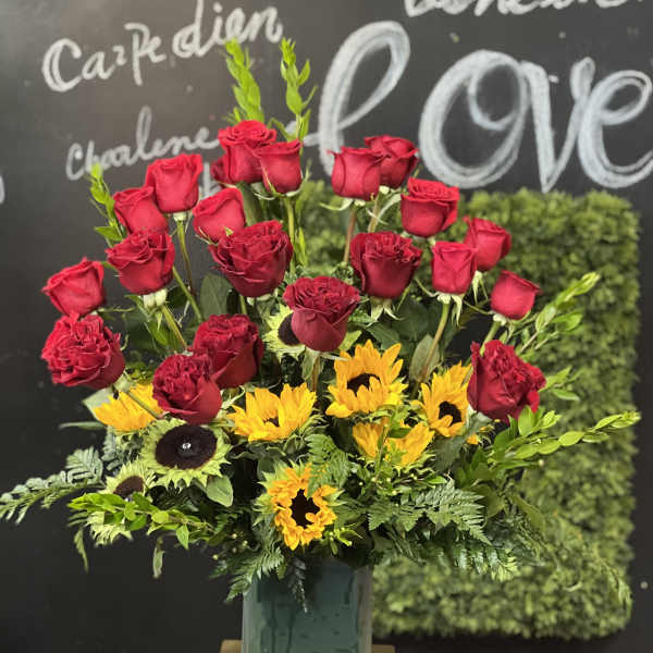 Red roses and yellow sunflowers in a glass vase