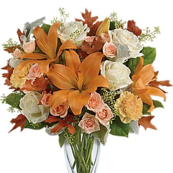 Orange lilies and peach roses in a clear glass vase