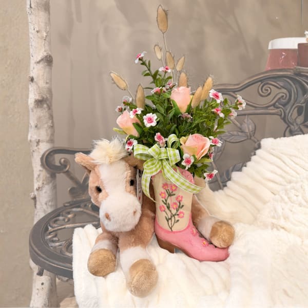 Plush horse beside a small floral arrangement in a pink boot vase
