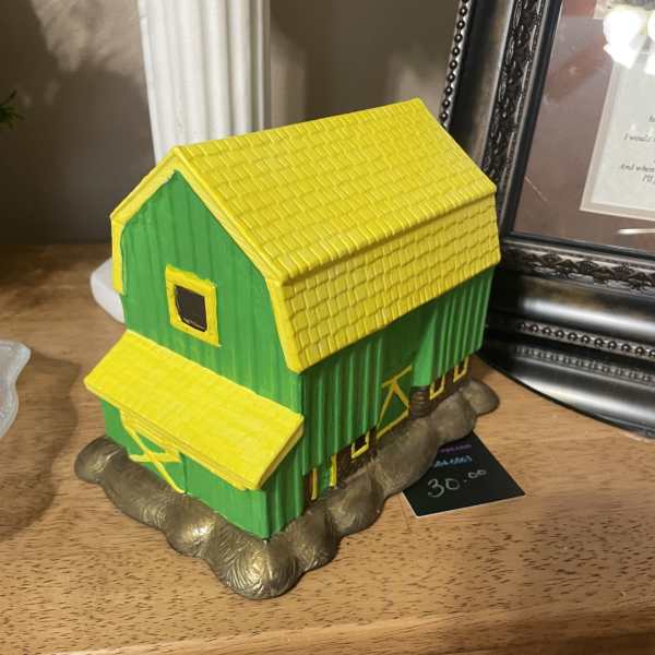 Decorative green and yellow house figurine on a shelf