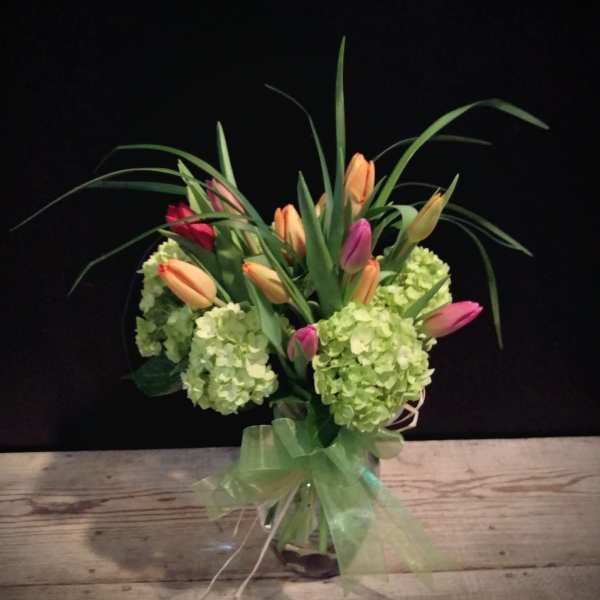 Bouquet of pink and peach tulips with green hydrangeas in a glass vase