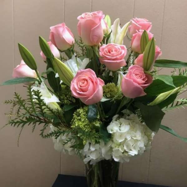Pink roses and white lilies arranged with white hydrangea in a vase
