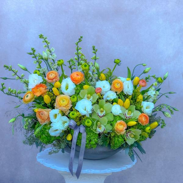 Large mixed floral arrangement in a low bowl with white, yellow, and orange blooms