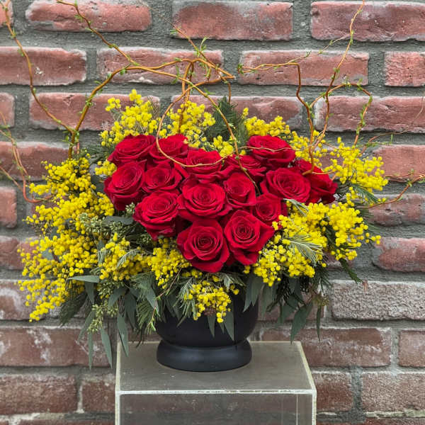 Red roses arranged with yellow filler flowers in a black vase
