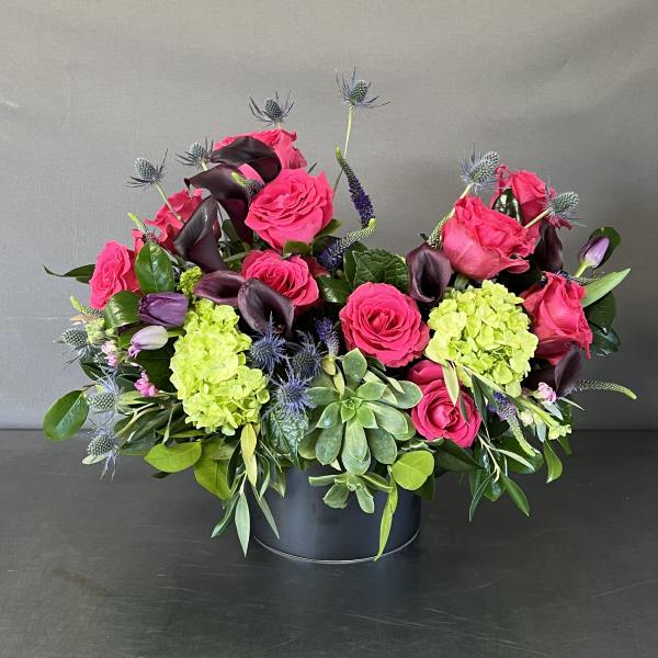 Pink roses and green hydrangeas in a black container with purple accents