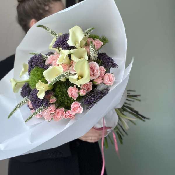 Bouquet of pink roses and pale calla lilies wrapped in white paper