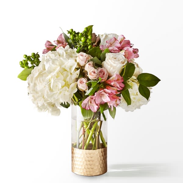 Pink and white bouquet in a clear glass vase with a textured gold wrap