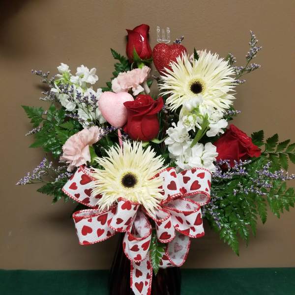 Heart-themed bouquet with red roses, white daisies, and a heart ribbon in a vase