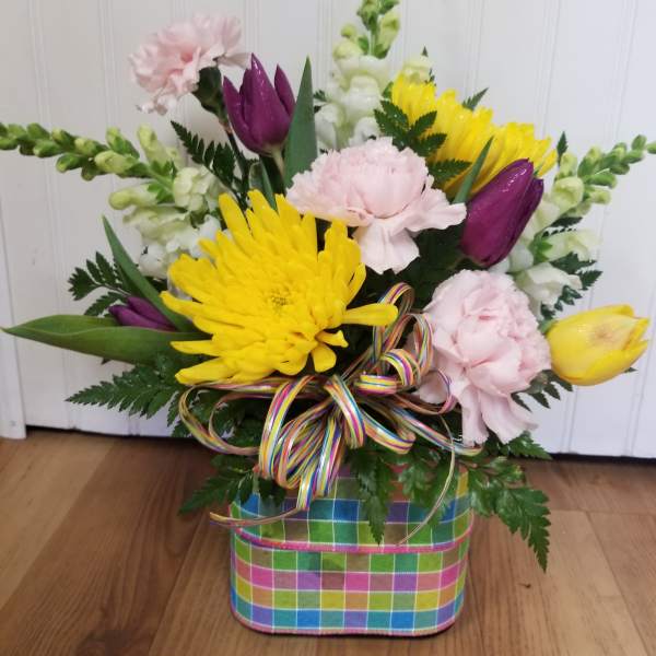 Colorful mixed flower arrangement in a plaid basket with a ribbon bow