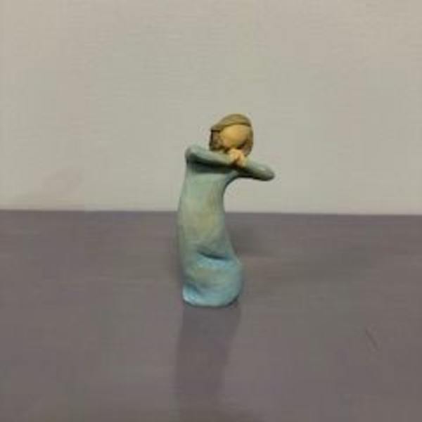 Small figurine of a child in a blue dress with arms crossed