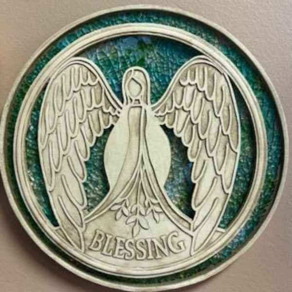 Round angel medallion with the word Blessing on a blue-green background