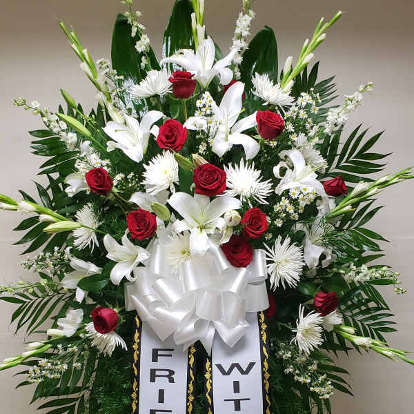 Standing sympathy spray with red roses, white lilies, and ribbon banners