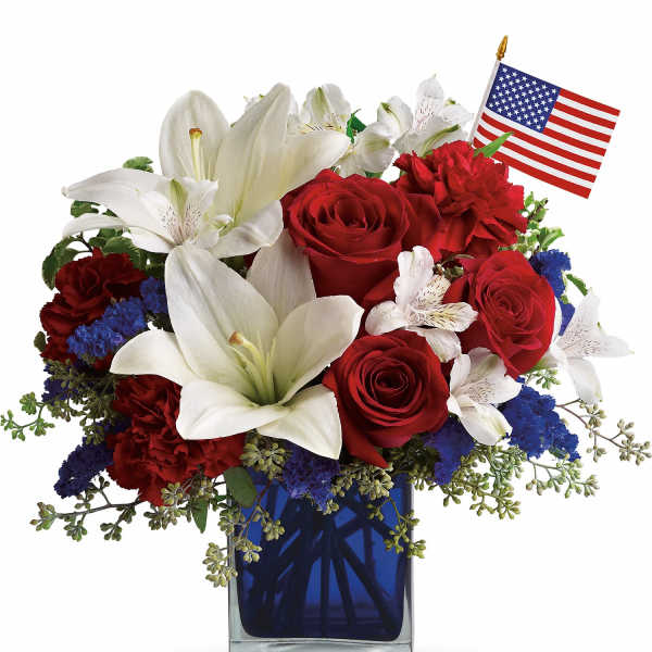Red roses and white lilies in a blue vase with a small American flag