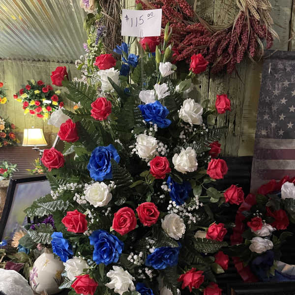 Tall arrangement of red, white, and blue roses with greenery