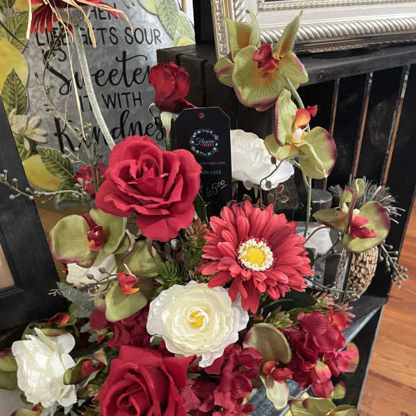 Arrangement of red roses, white blooms, and orchids in a decorative container