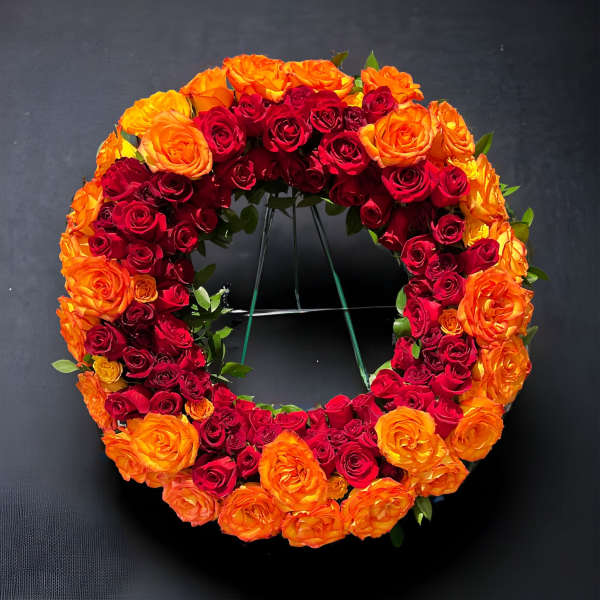 Circular wreath of red and orange roses on a stand